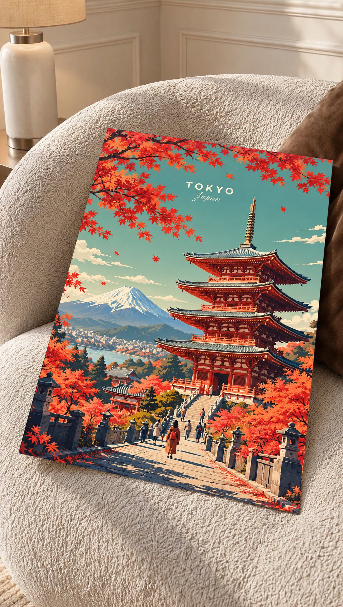 Red maple travel poster on a couch showing Tokyo pagoda, street scene and Mount Fuji