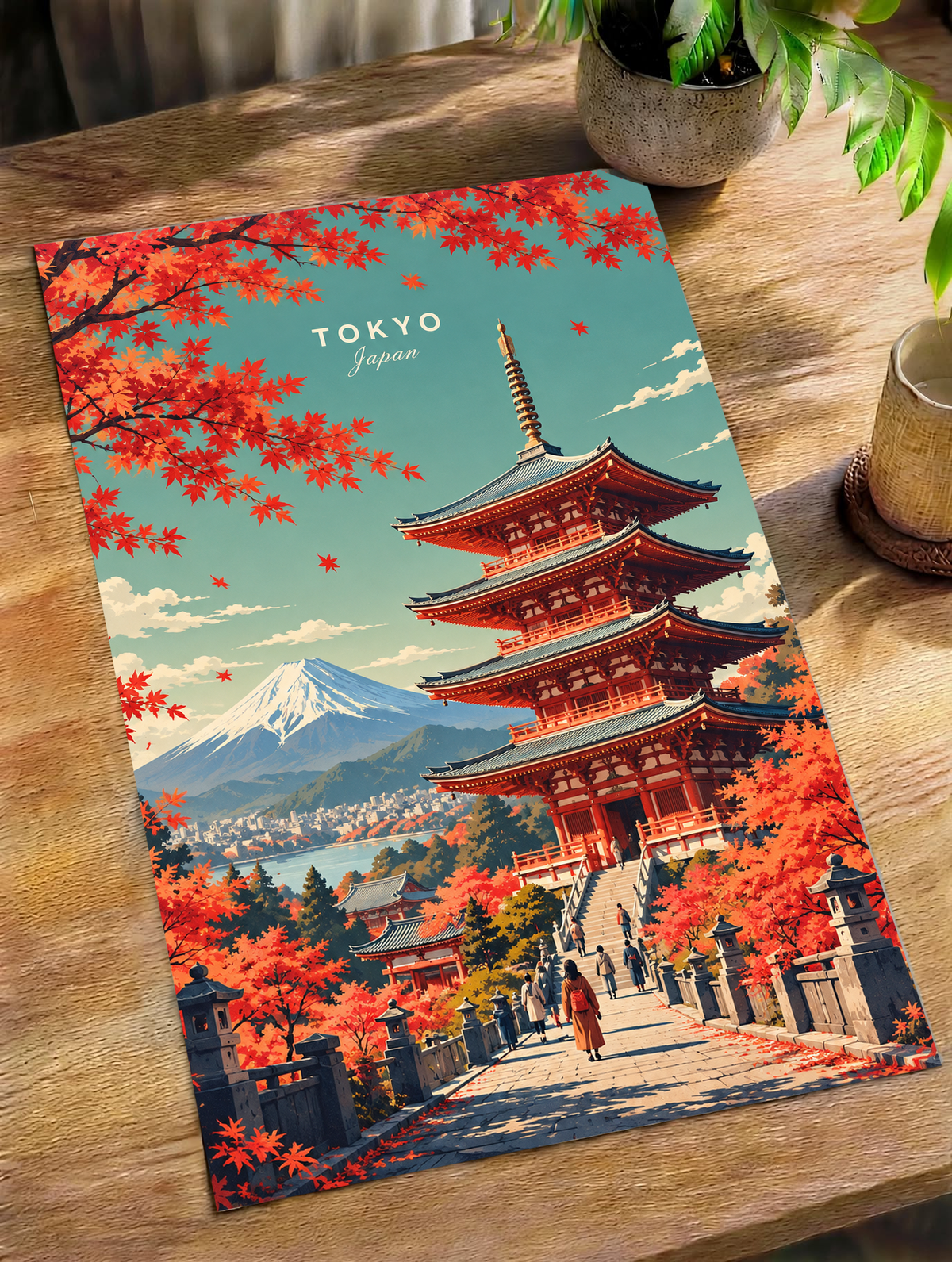 Folded red maple and Tokyo pagoda poster lying on a wooden table with Mount Fuji view