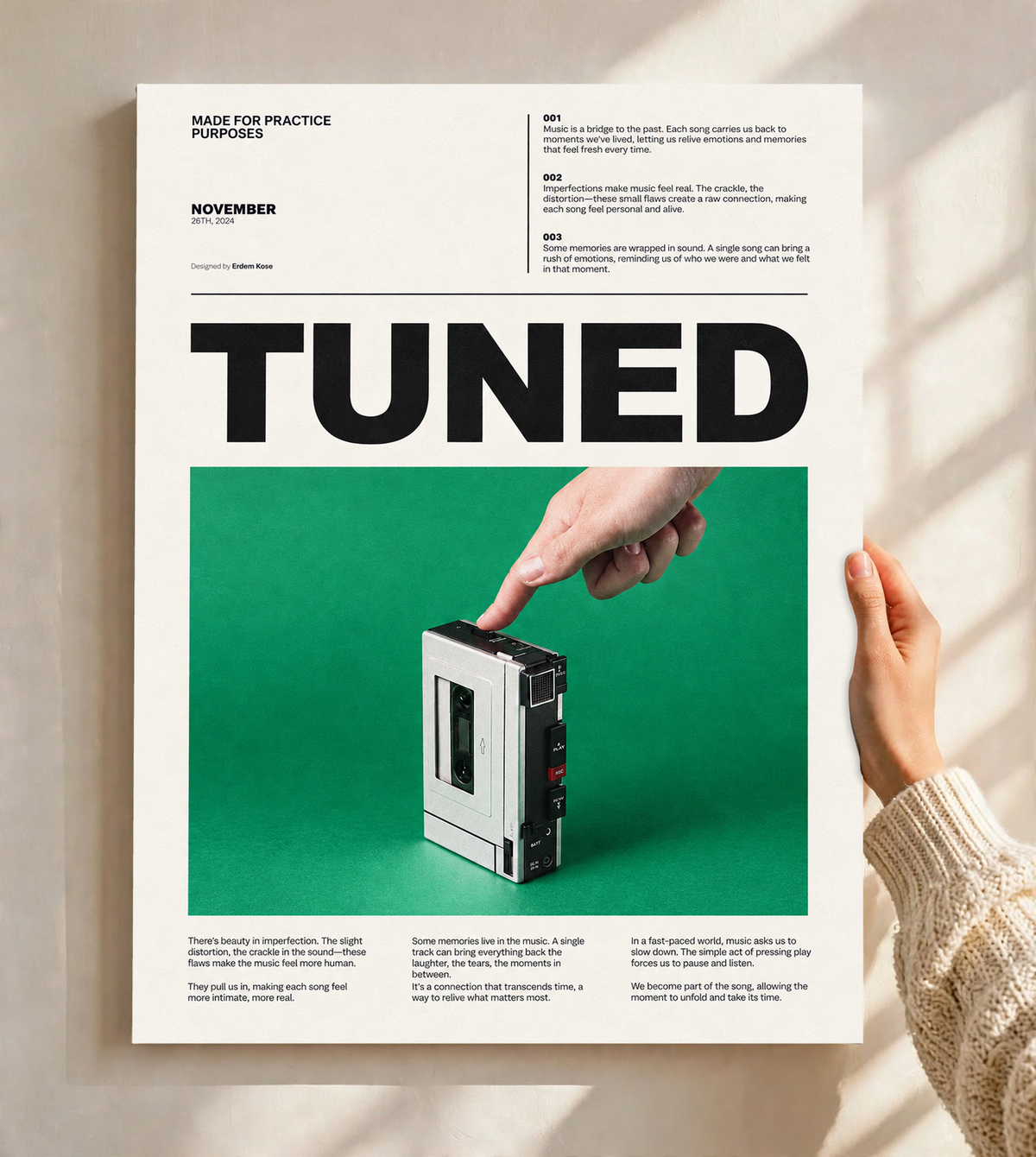 A hand pressing a portable cassette player against green beneath Tuned typography as an unframed poster held against a pale sunlit wall