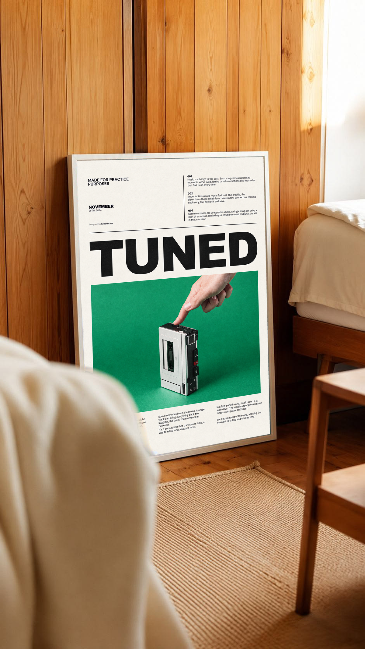 A hand pressing a portable cassette player against green beneath Tuned typography in a white frame leaning against warm wooden wall panels