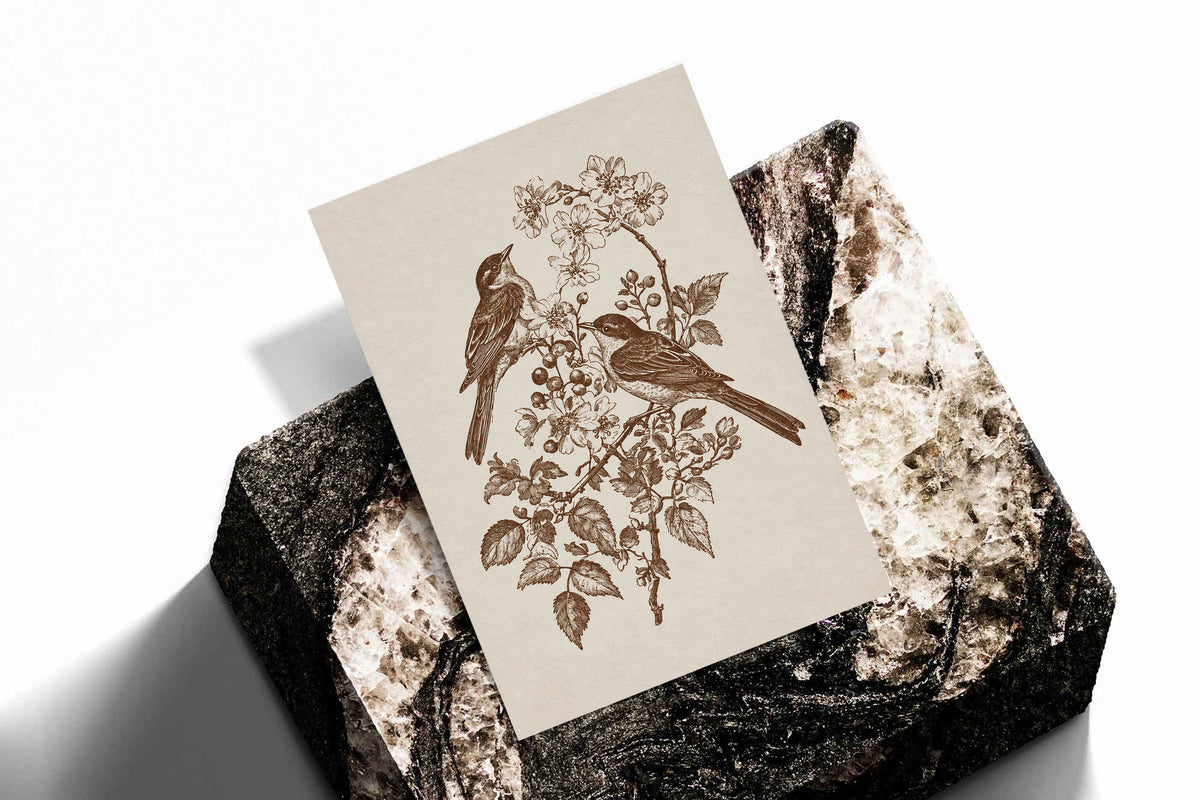 Two birds perched on a flowering branch with leaves and blossoms in sepia as an unframed print standing on a stone plinth against white