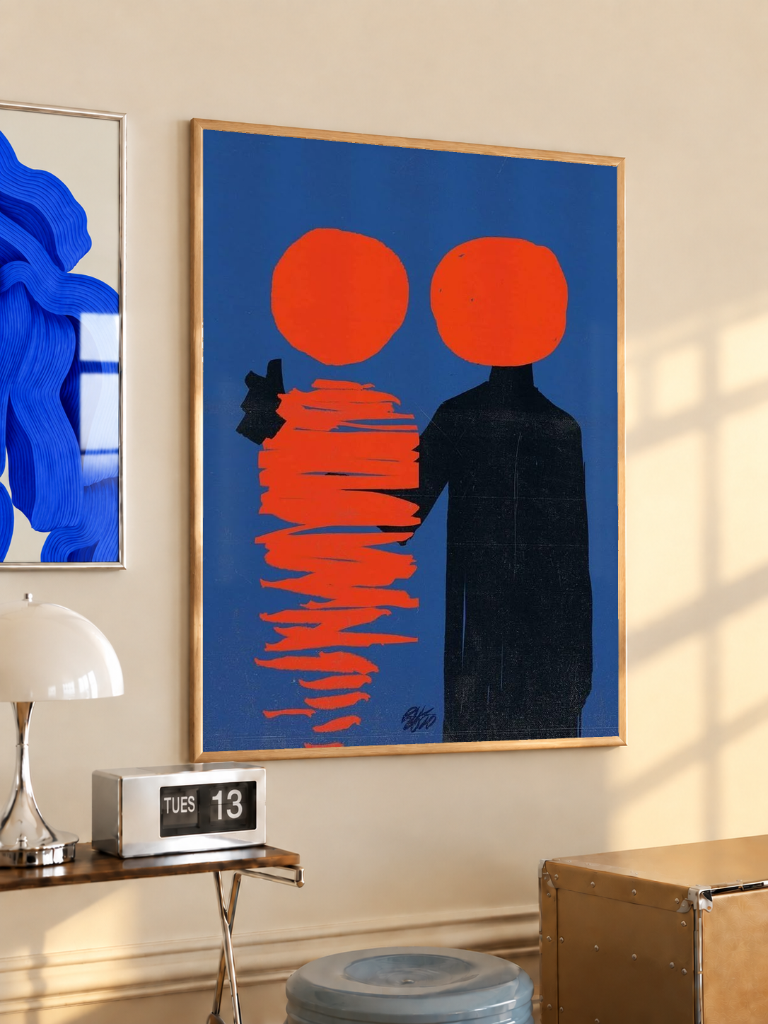 Gold-framed abstract poster with two orange circles, a black figure, and red stacked lines