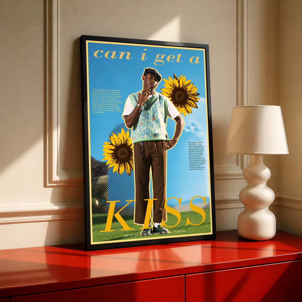 Tyler the Creator portrait collage with sunflowers and Can I Get a Kiss lettering; black framed print on a red cabinet
