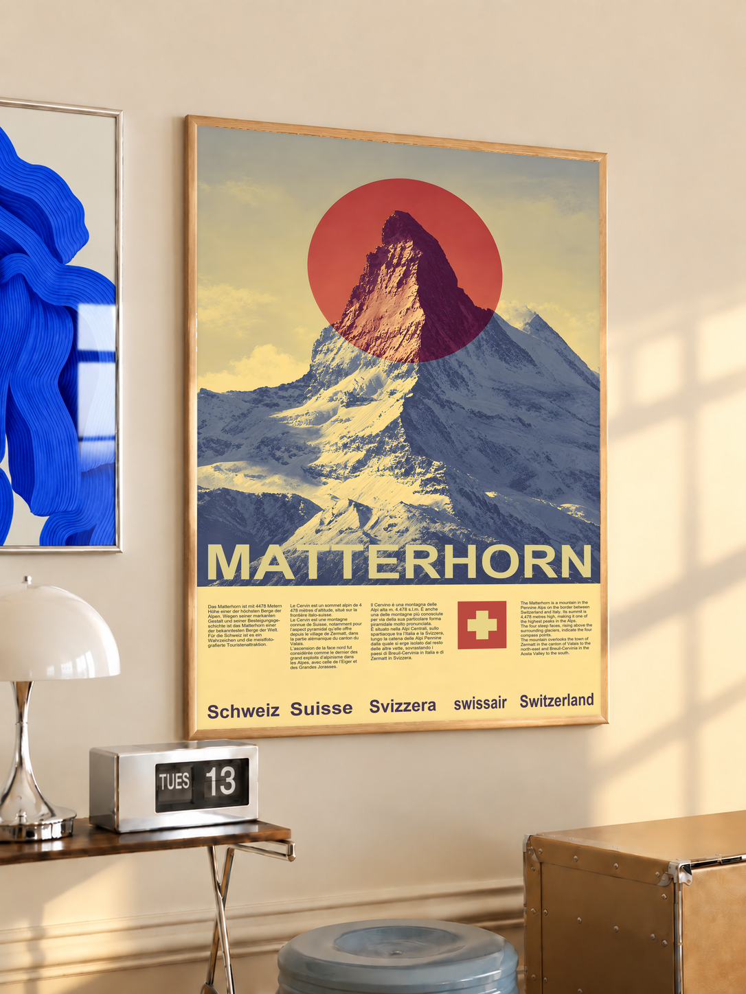 Yellow and navy Matterhorn mountain with a red sun and Swiss cross; oak framed print in a desk setting
