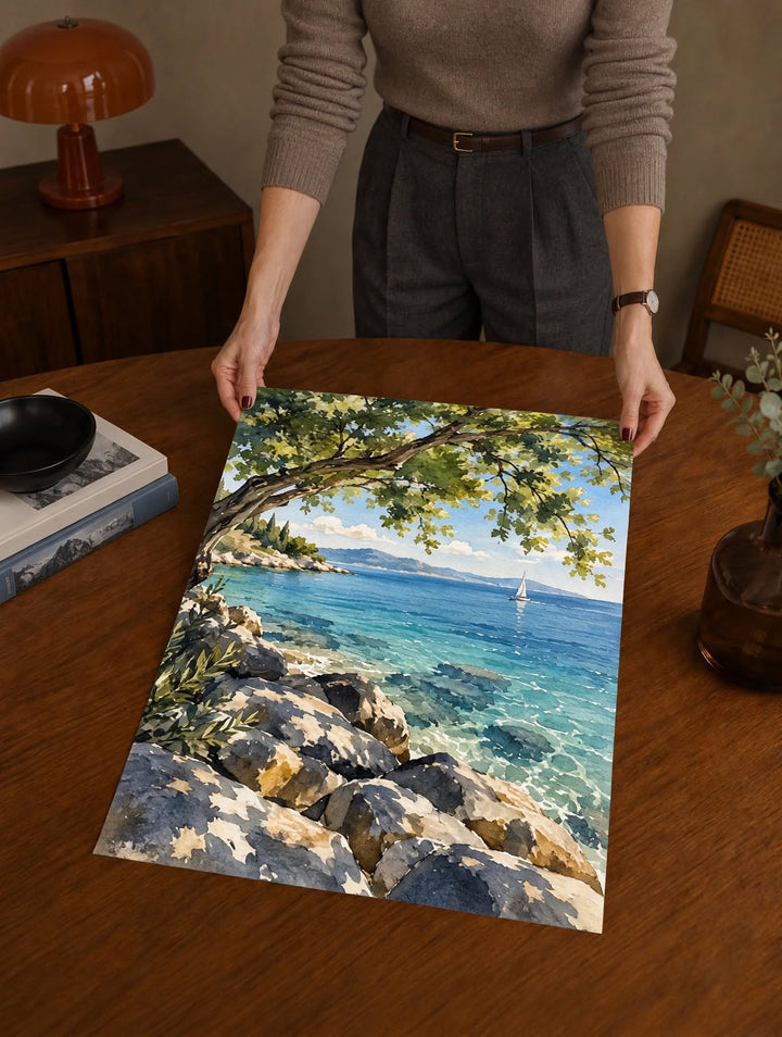 Mediterranean Coast Watercolor Art Print laid on a dark wooden table, capturing the contrast between shaded trees and luminous sea