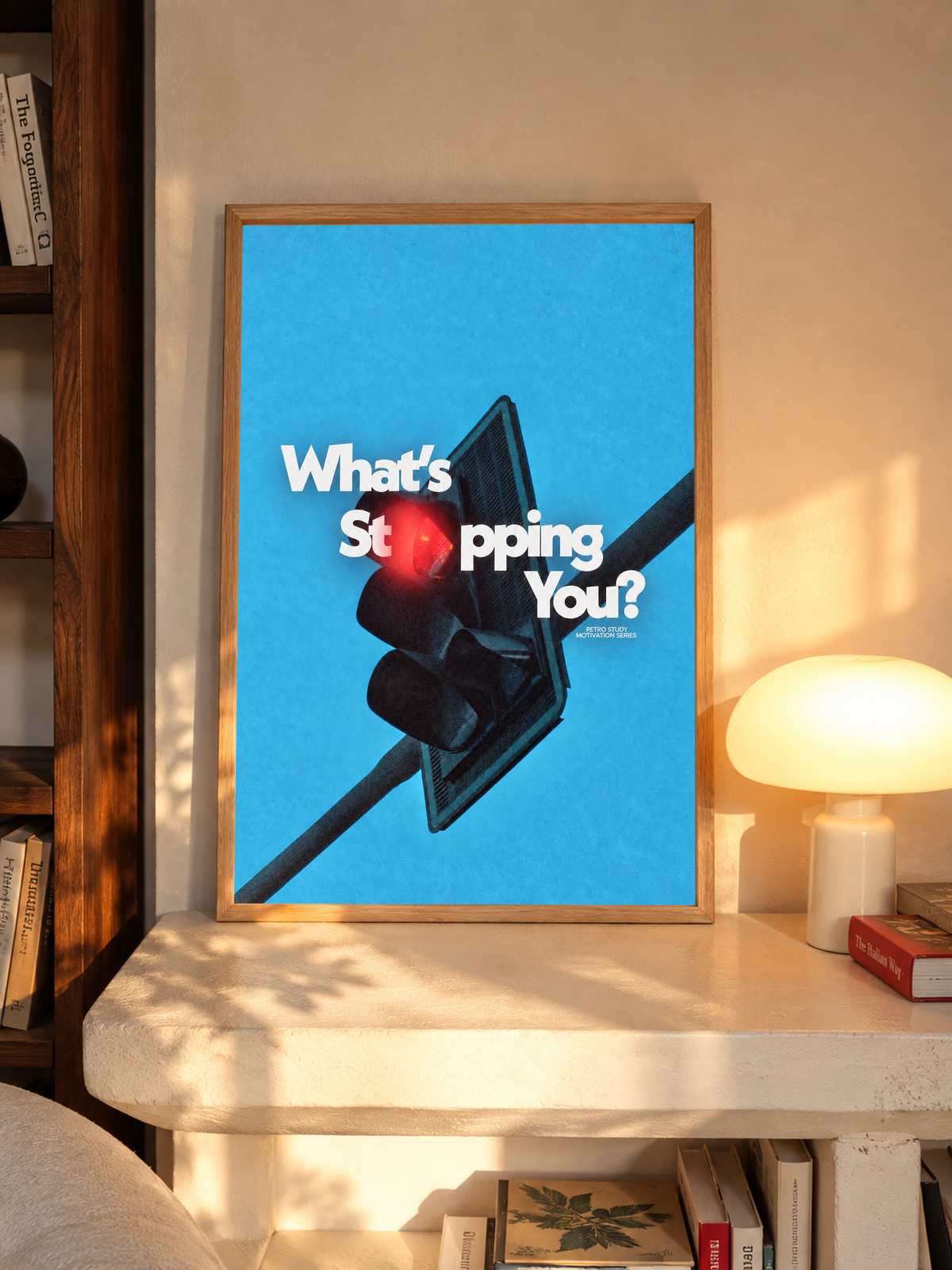White What's Stopping You lettering over a red traffic light against blue sky in an oak frame above a pale wooden sideboard beside a glowing lamp
