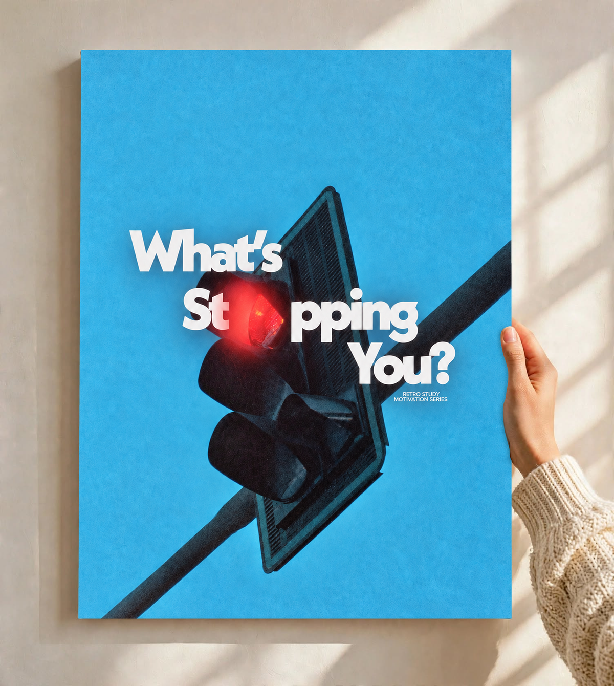 White What's Stopping You lettering over a red traffic light against blue sky as an unframed poster held against a pale sunlit wall