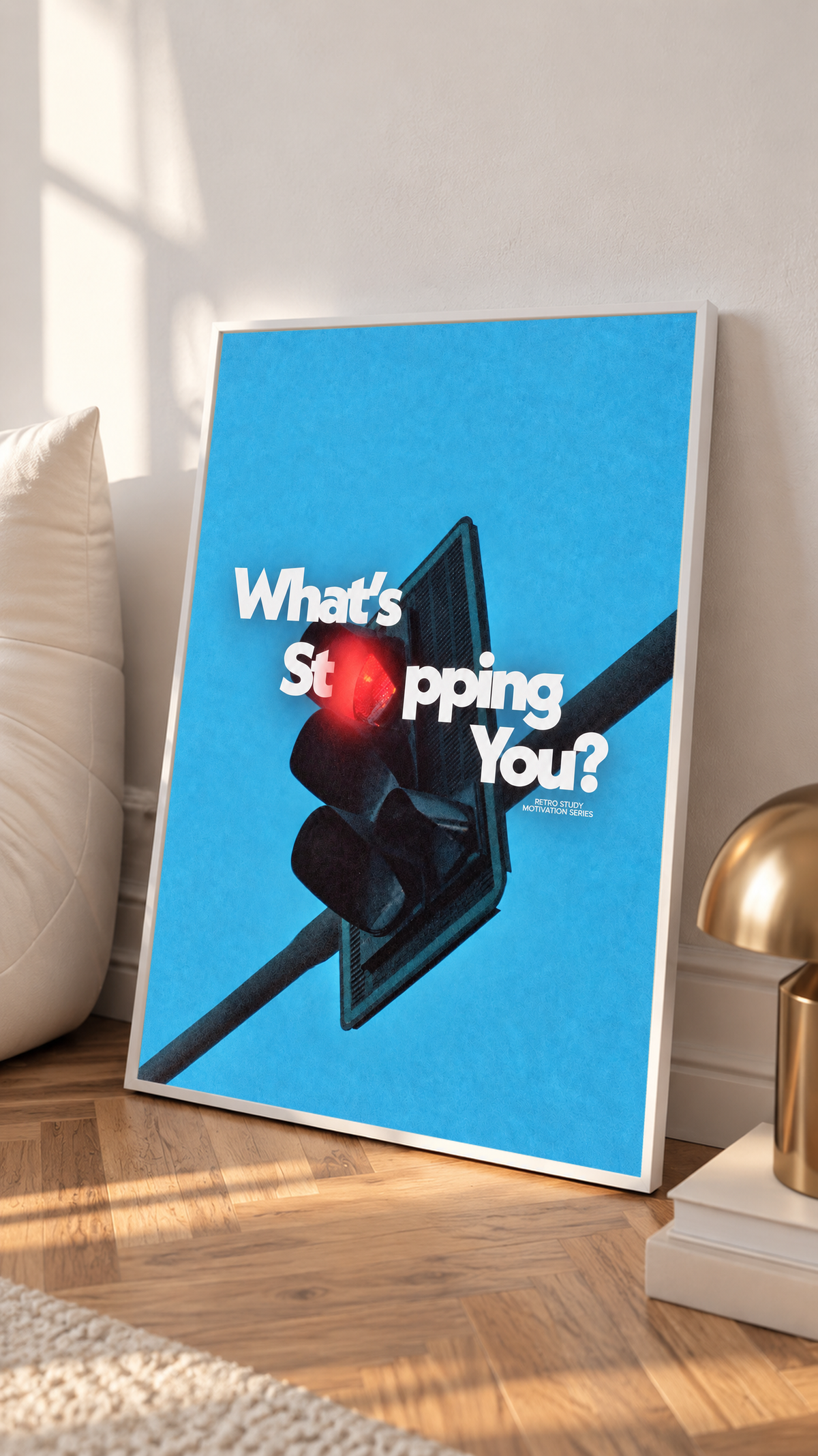 White What's Stopping You lettering over a red traffic light against blue sky in a white frame on a sunlit floor beside a white cabinet
