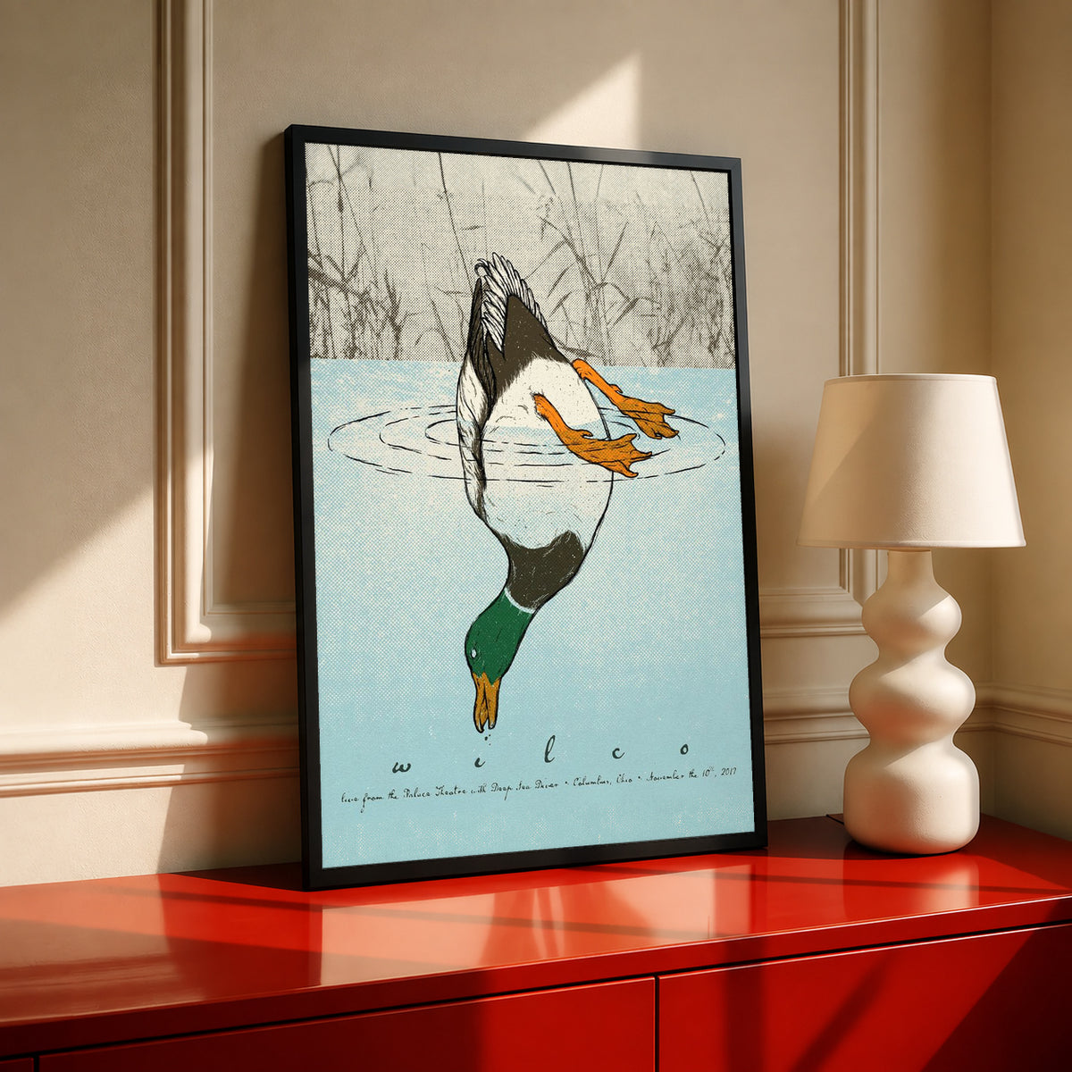 Black-framed diving duck art print with blue water, orange ducklings, and reeds