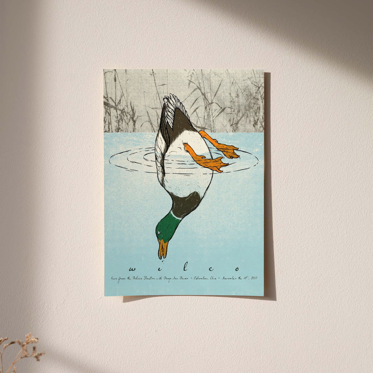 Small framed diving duck art print with blue water and orange ducks on a light wall