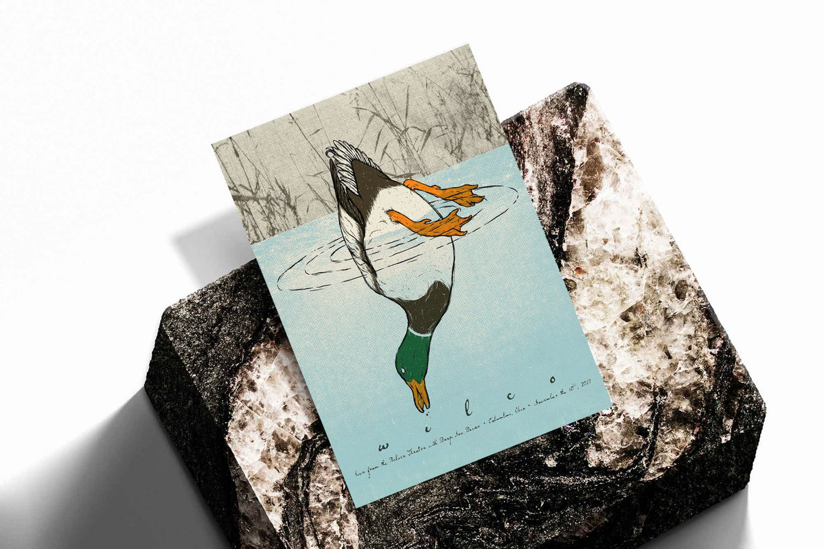 Diving duck art print with blue water and orange ducks on a dark stone display