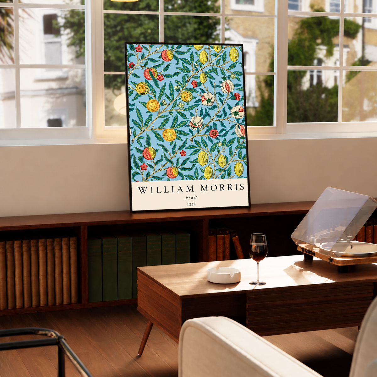 William Morris Fruit botanical pattern with yellow fruit and green leaves on pale blue in a black frame on a cabinet beside a window and record player