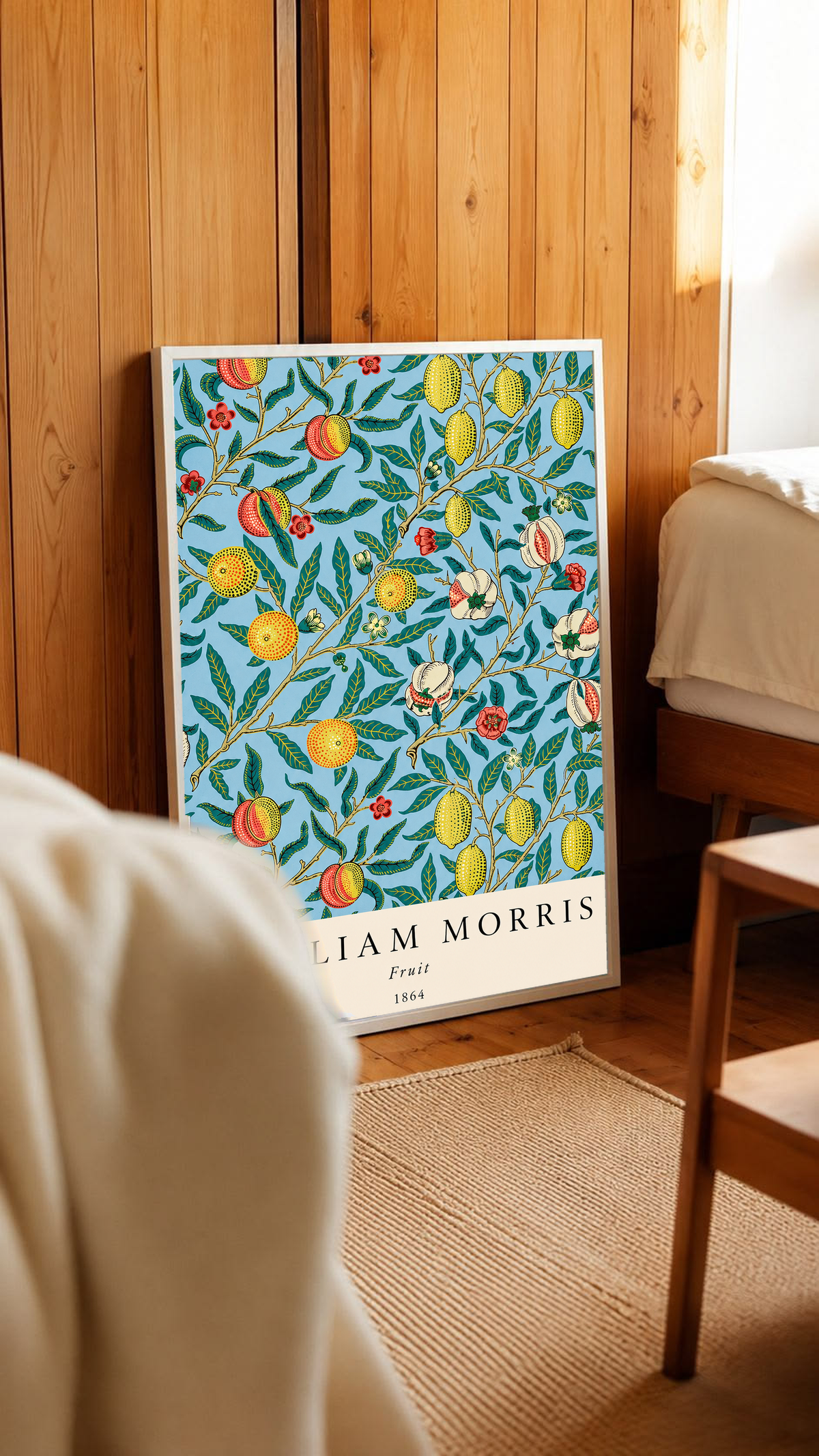 William Morris Fruit botanical pattern with yellow fruit and green leaves on pale blue in a white frame in a wood-panelled bedroom