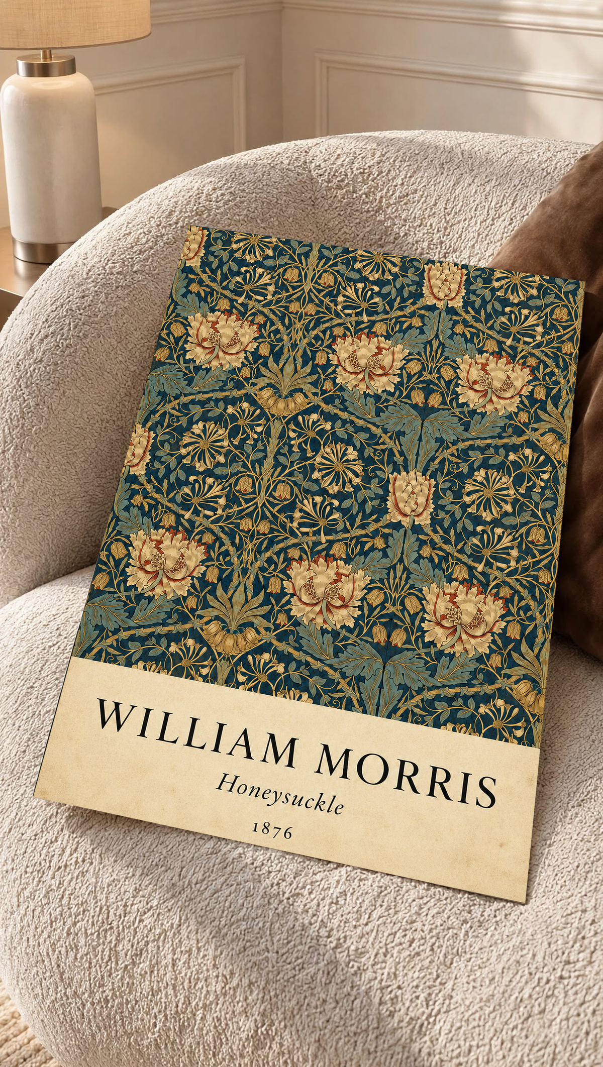 William Morris Honeysuckle floral pattern with gold and pink blooms on dark teal as an unframed print resting on a boucle chair