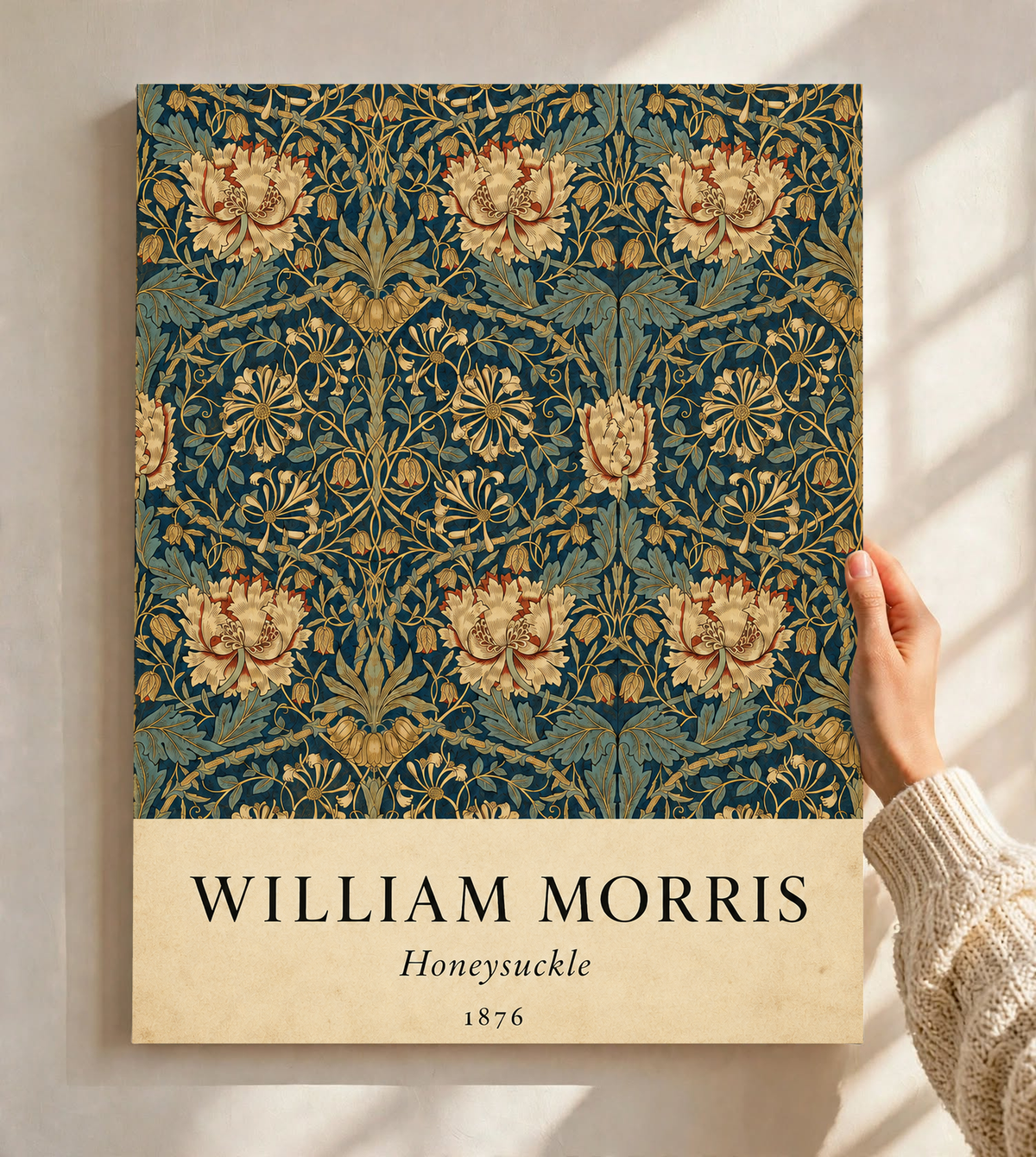 William Morris Honeysuckle floral pattern with gold and pink blooms on dark teal as an unframed print held against a pale wall in a close view