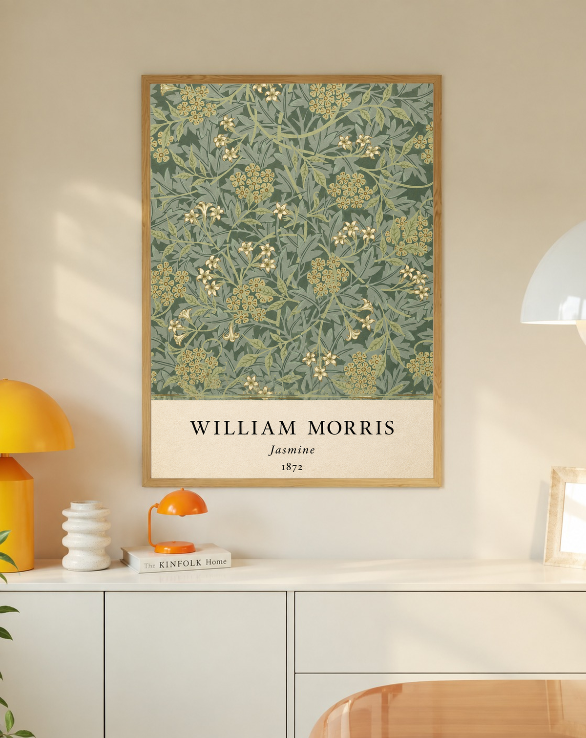 William Morris Jasmine sage and olive foliage with pale yellow flowers in an oak frame on a wall above a white cabinet beside a yellow lamp