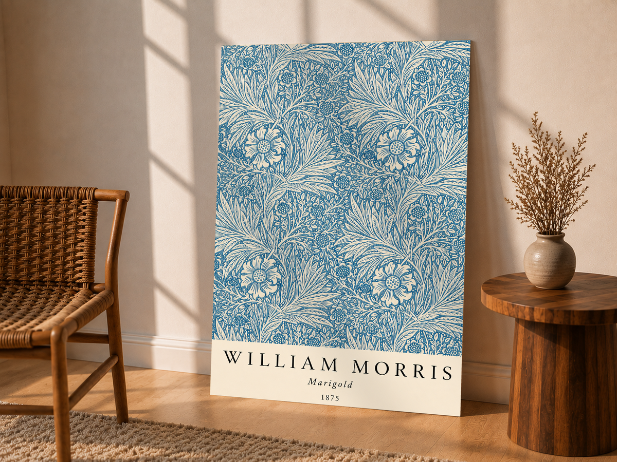 William Morris Marigold blue and cream floral leaf pattern as an unframed display leaning beside a wicker chair and side table