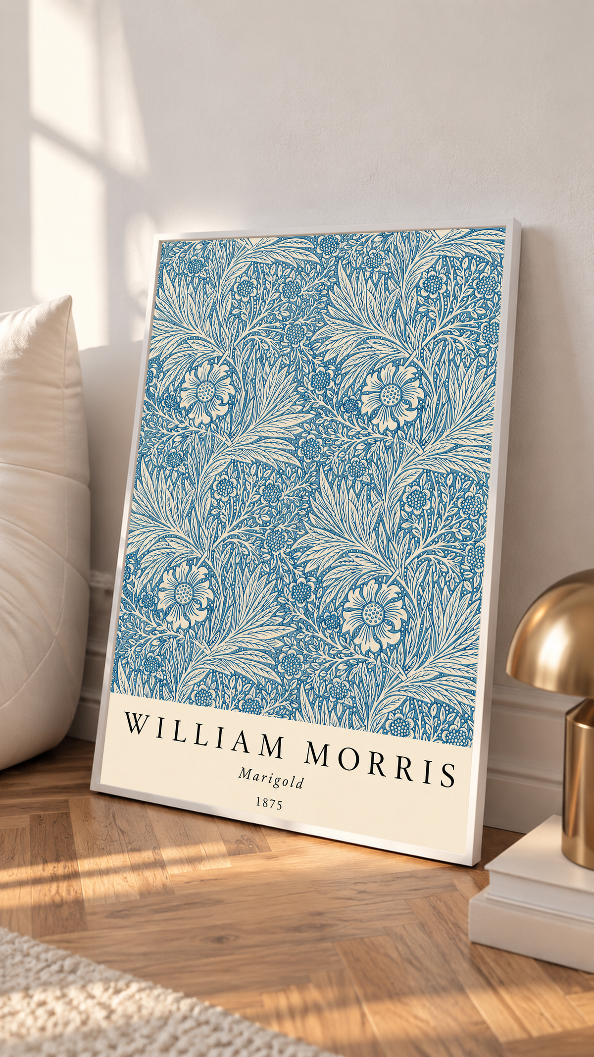 William Morris Marigold blue and cream floral leaf pattern in a white frame leaning on a sunlit floor beside a brass lamp