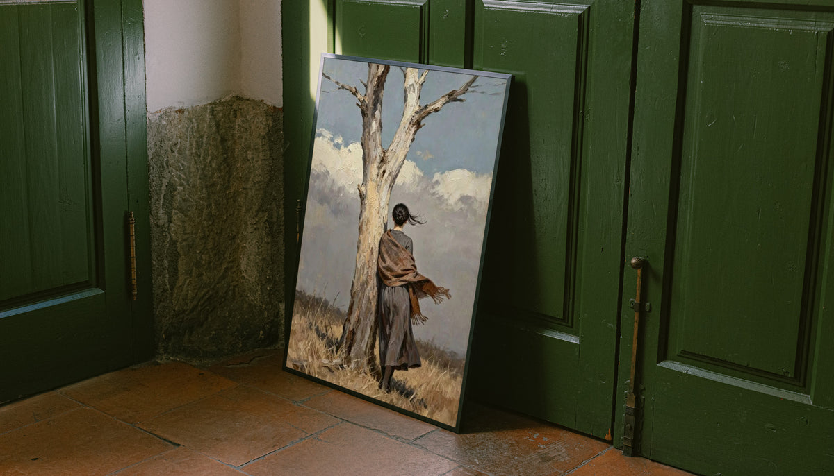 A woman in a long dark dress and brown shawl beside a pale tree in a windswept field leaning on the floor against dark green wall panelling