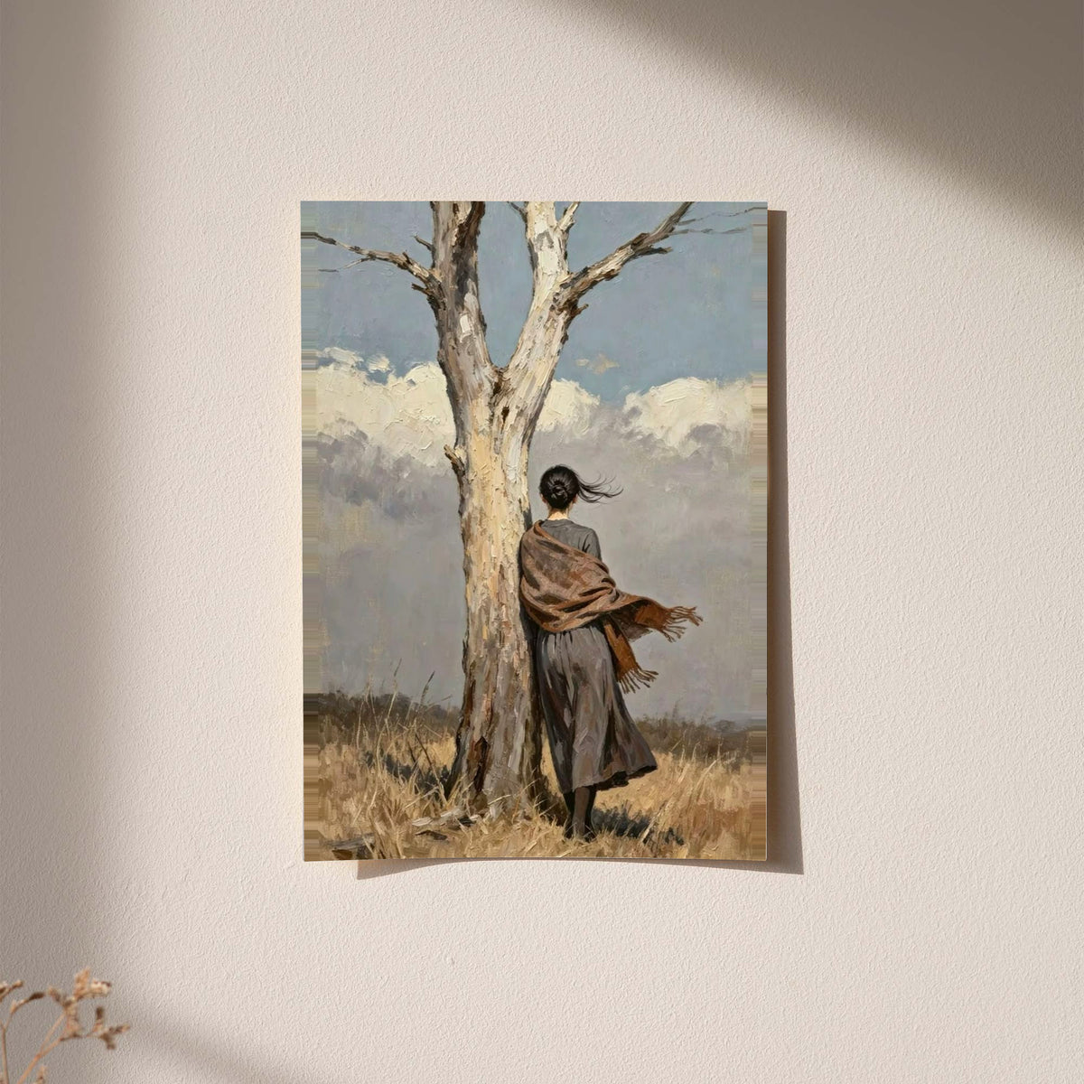 A woman in a long dark dress and brown shawl beside a pale tree in a windswept field displayed without a visible frame on a softly lit pale wall