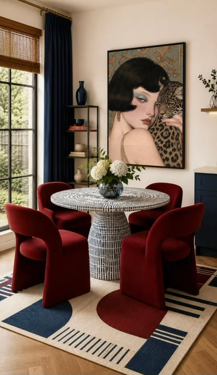 Framed leopard and woman art on wall with wood frame, shown above red dining chairs