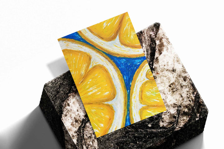 Oversized yellow lemon slices with white rinds against cobalt blue as an unframed print resting at an angle on a dark stone display