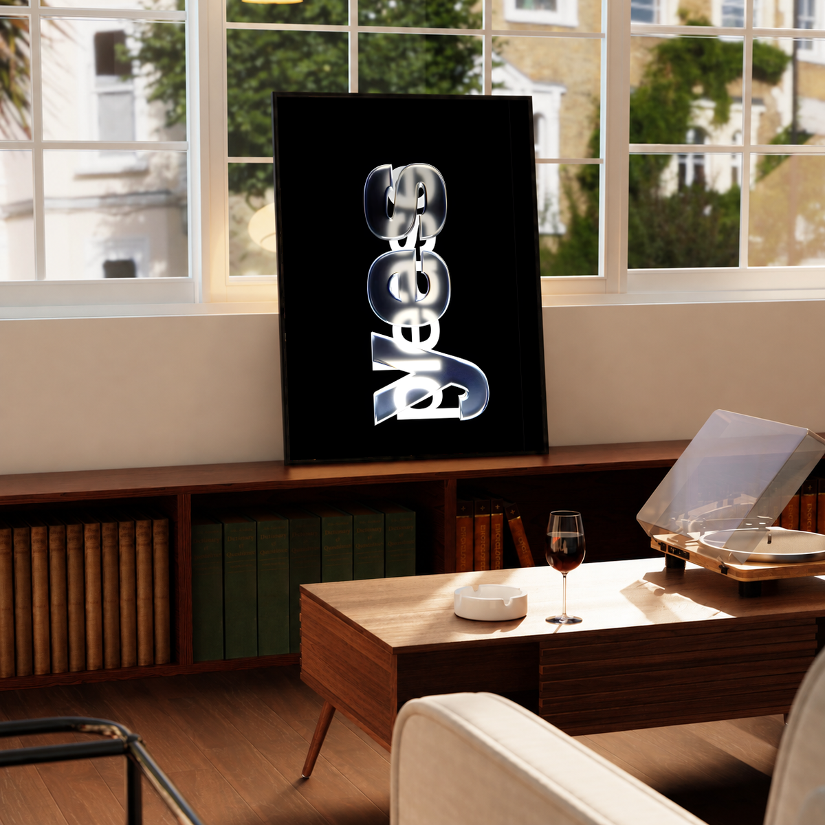 Yes Please lettering with reflective silver yes and overlapping white please on black, styled in a black frame above a wood console with books and a record player