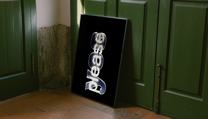 Yes Please lettering with reflective silver yes and overlapping white please on black, styled in a black frame against dark green paneled doors above orange floor tiles