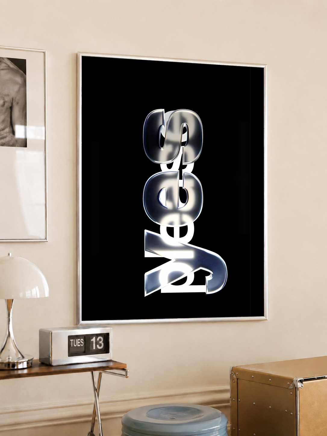 Yes Please lettering with reflective silver yes and overlapping white please on black, styled in a light frame on a cream wall beside a white dome lamp and glass side table