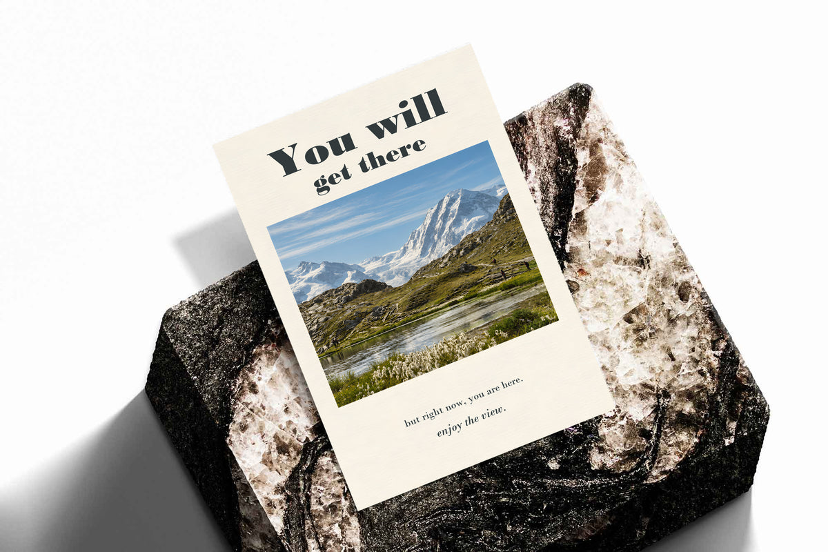 Mountain lake poster displayed against a rock